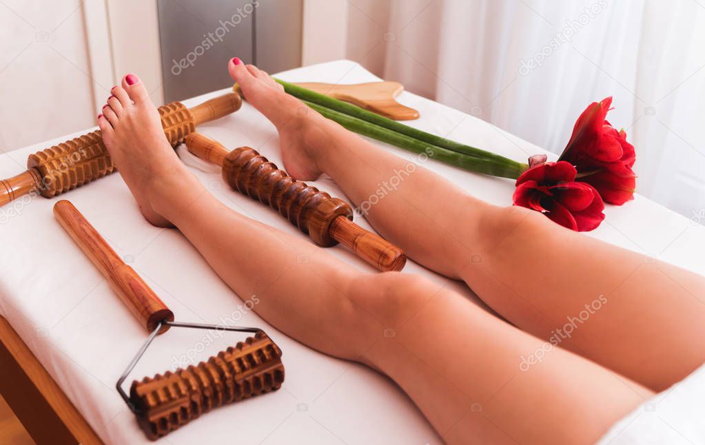 Legs of beautiful young lady on maderotherapy anticellulite massage treatment of leg at beauty spa salon. Cropped picture.