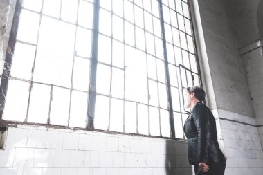 Olgun akıllı mimar eski salondaki büyük pencereden dışarı bakar.