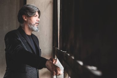 Olgun yakışıklı erkek eski salonun penceresinden bakıyor. 