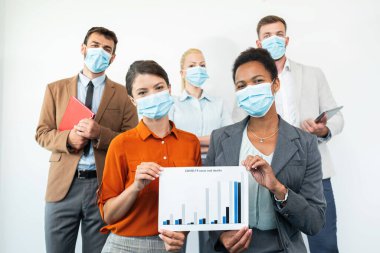 Bir grup öğrenci kameraya bakıyor, maske takıyor ve koronavirüs yüzünden istatistik gösteriyor.