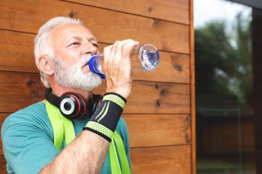 Kıdemli sporcu egzersiz molasında su içiyor. Sağlıklı yaşam tarzı konsepti.