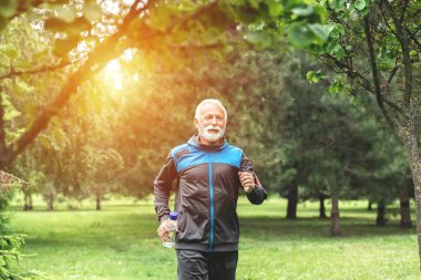 Yaşlı adam parkta koşuyor, sağlıklı yaşam tarzı konsepti.