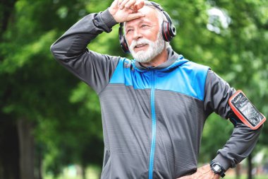 Parkta koştuktan sonra dinlenen yorgun adam, sağlıklı yaşam tarzı konsepti.