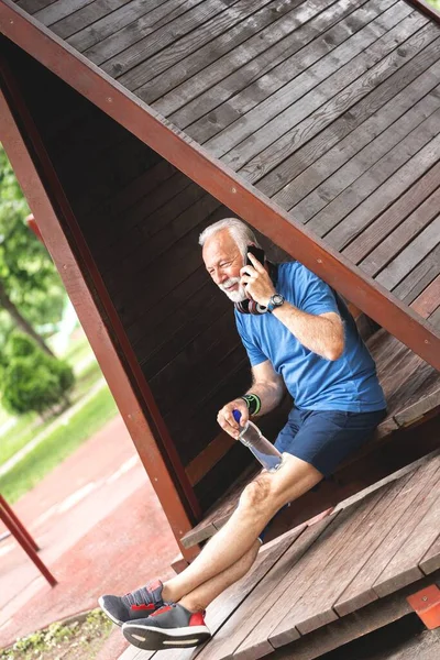 Senior sportsman talking on mobile phone at park, healthy lifestyle concept