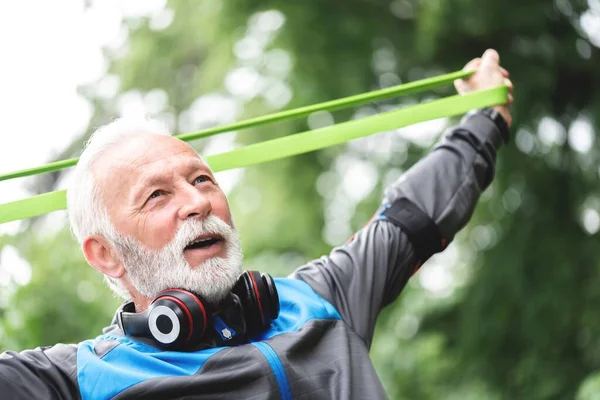 Senior sportsman exercising with resistance band at park,healthy lifestyle concept
