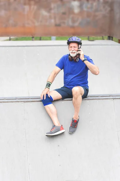 Senior sportsman talking on phone while relaxing during exercise, healthy lifestyle concept