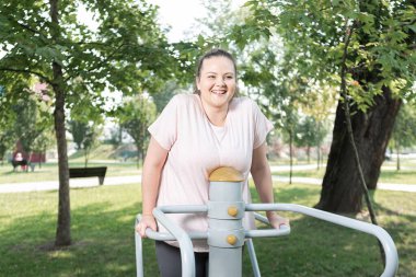 Parkta spor yapan şişman bir kadın.