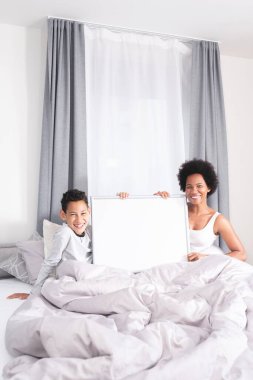 Anne ve oğlu yatakta boş tahta tutuyorlar.