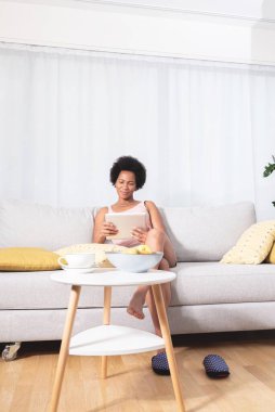 Kanepede dijital tablet kullanan kadın