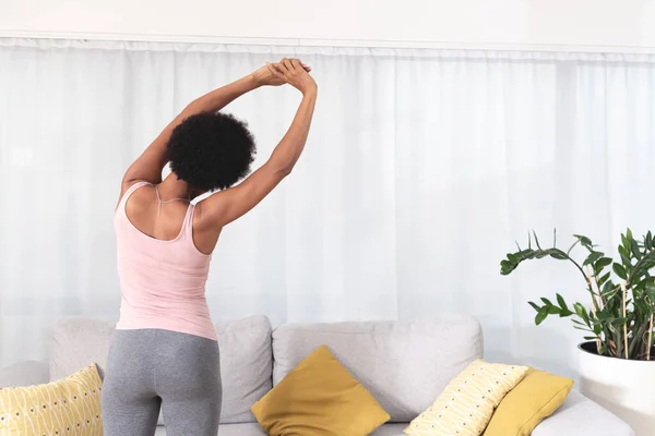 Rear view of woman stretching at home