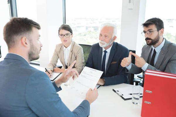 Business people interviewing male applicant at office
