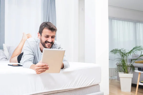 Hombre Feliz Usando Tableta Digital Acostado Cama Casa — Foto de Stock