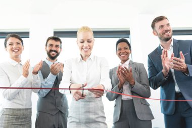 Çeşitli iş adamları kırmızı kurdeleyi kesiyor ve yeni bir iş girişimine girişiyor.