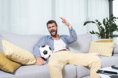 Genç adam oturma odasında futbol turnuvasını izlerken hayal kırıklığına uğradı.