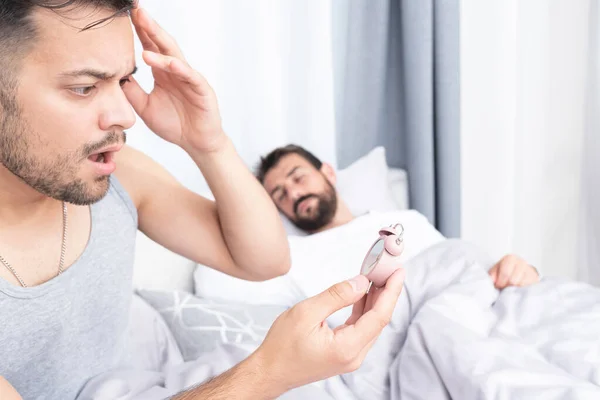 Joven Preocupado Por Mirar Despertador Mientras Novio Duerme Cama — Foto de Stock