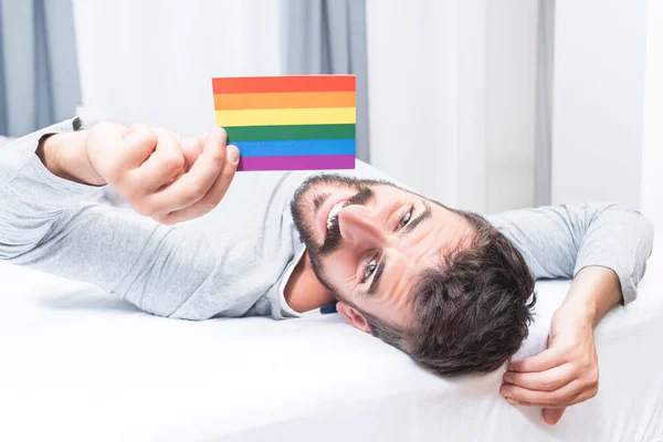 Genç Adam Evde Yatakta Yatarken Gökkuşağı Renkli Gay Sembolünü Gösteriyor — Stok fotoğraf