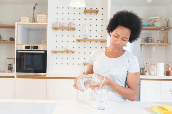 Mujer Afroamericana Vertiendo Agua Vaso Frasco Cocina —  Fotos de Stock