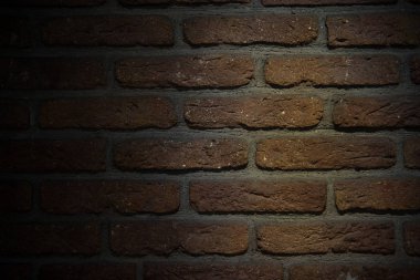 Kahverengi tuğla duvar arka plan ile düşük ışık. Görünümü gölgeler kadar kapatın.