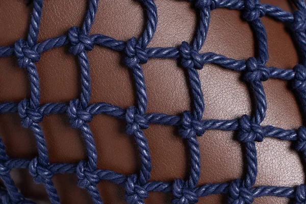 Luxury brown leather covered with blue rope net. Beautiful background. Closeup.