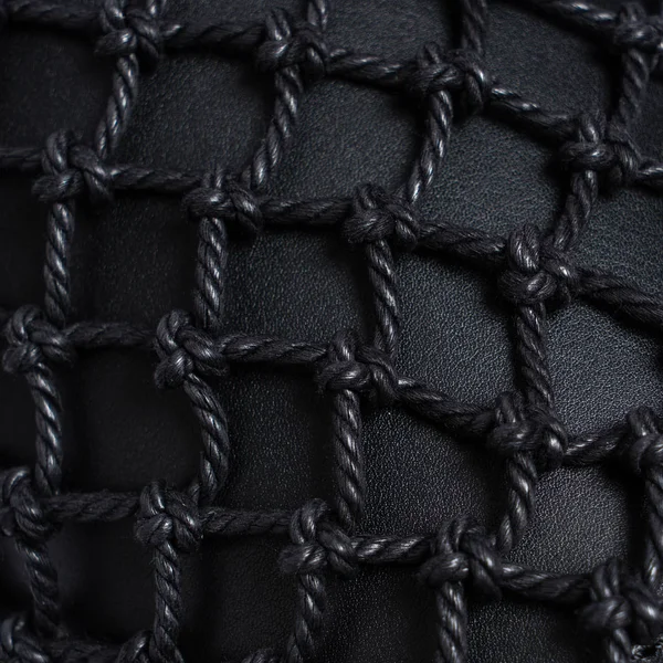 Luxury black leather covered with black rope net. Beautiful background. Closeup.