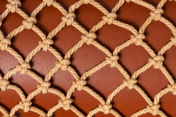 Luxury brown leather covered with beige rope net. Beautiful background. Closeup.