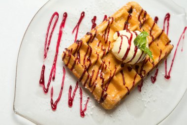 Dondurma ve cam plaka ve beyaz zemin üzerine nane ile geleneksel Belçika waffle. Reçel ile drizzled. Yakın çekim.