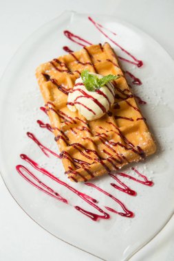 Dondurma ve cam plaka ve beyaz zemin üzerine nane ile geleneksel Belçika waffle. Reçel ile drizzled. Yakın çekim.