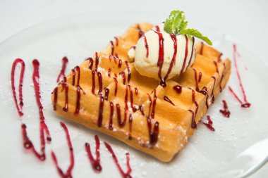 Dondurma ve cam plaka ve beyaz zemin üzerine nane ile geleneksel Belçika waffle. Reçel ile drizzled. Yakın çekim.