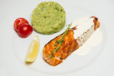 Lezzetli ızgara somon Biftek soslu beyaz tabakta rosemary ile dekore edilmiştir. Hizmet ile süsleyin. Ispanaklı patates püresi, limon ve kiraz domates.