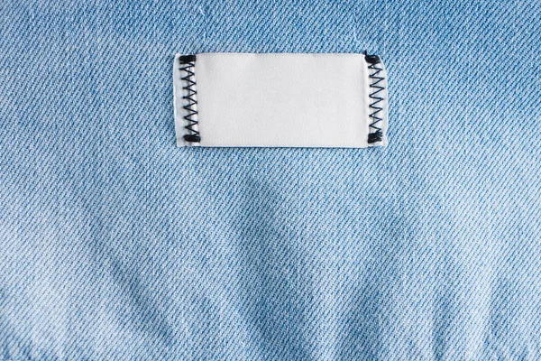 Blank White Cotton Label Stitched Thread Blue Jeans Texture Closeup — Stockfoto