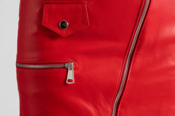 Red leather skirt on white background. Detailed closeup on zipper pocket and clasp.