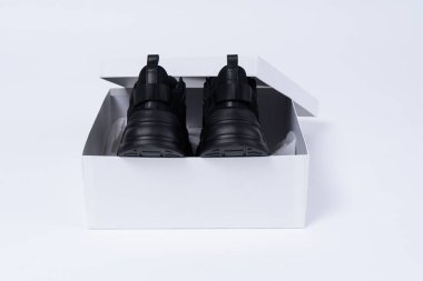 İki siyah modern ayakkabı arkasına beyaz bir arka plan üzerinde beyaz bir kutu. Güzel bir hediye unboxing.