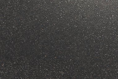 Gün batımında küçük taşlar ile asfalt yol dokusu. Koyu dokulu arka plan. Kopyalama alanı yla boşver.