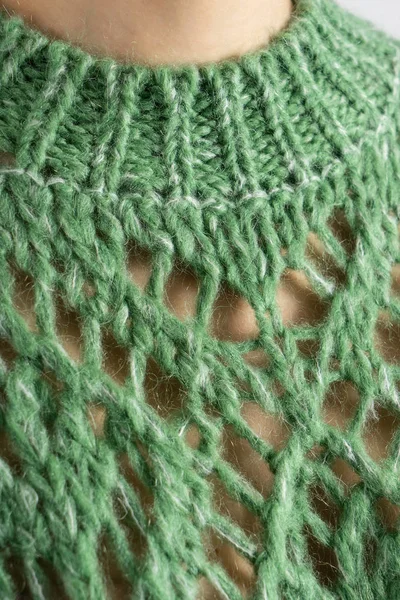 Green knitted woolen sweater texture on humans body. Colorful textured background.