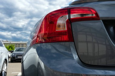 Araba arka ışık yakın çekim. Park yerinde ki mavi-gri bir otonun arkası. Araç Kiralama.