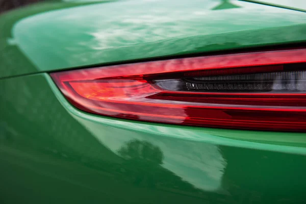 Back of a luxury green sports car. Closeup of a modern red backlight. Beautiful car body.