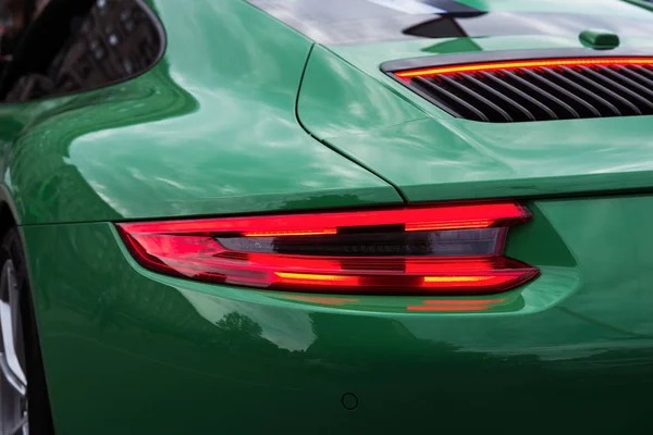 赤いバックライトが点灯したグリーンスポーツカー 高級車ボディのクローズアップ モダンなLedライト リアライトストリップ — ストック写真