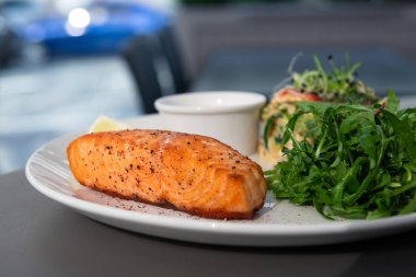 Arugula ve salata ile tarafında ızgara somon biftek. Restoranda beyaz bir tabak tabaktabaktabak tabaktabak tabaktabak tabaktabak tabak tabaktabak tabak tabak tabak tabak tabak tabak tabak tabak tabak tabak tabak tabak tabak tabak tabak tabak tabak tabak tabak tabak tabak tabak Bokeh ile yakın çekim.