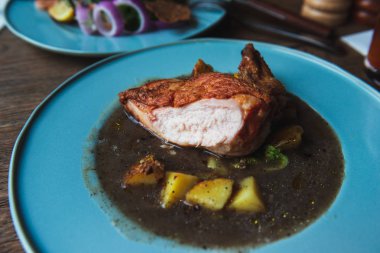 Patates ile bir çorba gevrek bronz deri ile pişmiş tavuk fileto. Ahşap bir masa üzerinde turkuaz plaka. Ev yapımı akşam yemeği. 