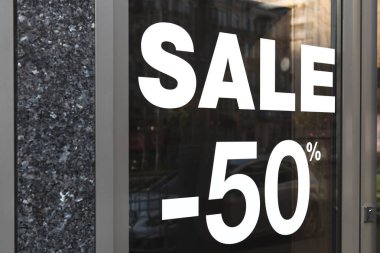 Bir perakende mağazasının camında satış tabelası. Beyaz renkli kaplamalı etiket. Metin eksi yüzde elli mevsimsel teklif. Özel teklif.
