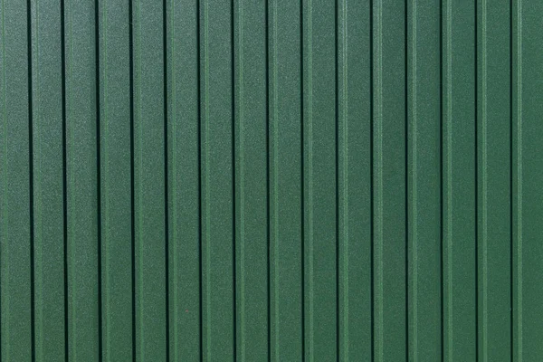 Green metal striped surface. Colorful fence with vertical lines. Empty background with copy space. Under construction. Linear background.