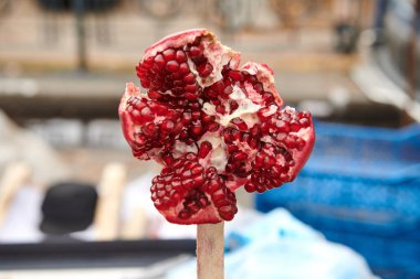 Marketteki çubukta nar açtık. Olgun meyvelerin sulanması. Doğal organik ürün yakın plan. Kırmızı tohumlar. Bokeh ile yakın çekim.