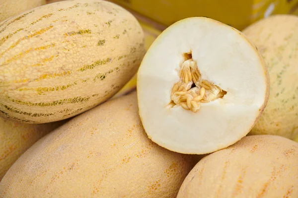 Ripe melon cut in half laying on a bunch of yellow melons. Melon with seeds. Degustation at the market.