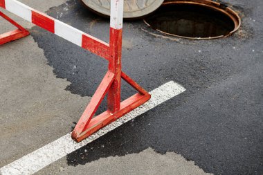 Bozulmadan sonra tamir sırasında kanalizasyon kapağını aç. Kamu hizmetleri için çalışıyorum. Tahta yol çiti. Kanalizasyondan su pompalıyorum. Yol tamiri konsepti fotoğrafı.