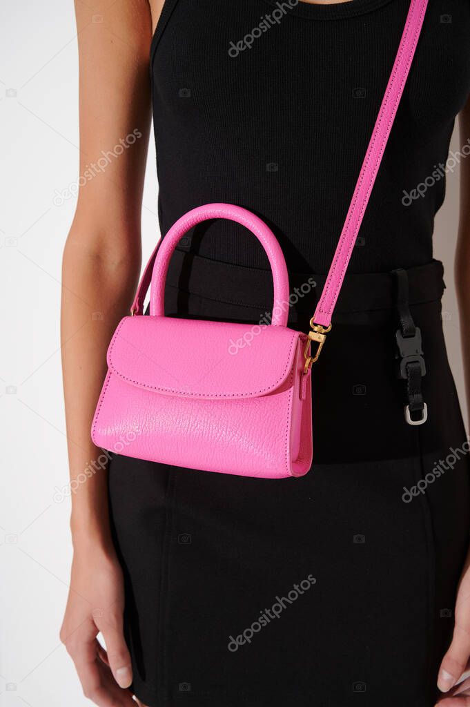 Girl in black dress with beautiful pink leather handbag. Luxury handmade bag with reptile effect. Fashionable modern accessory. Vertical photo.