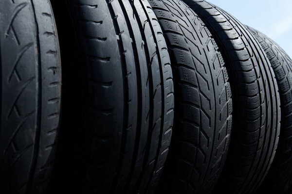 Stack of used tires at the car service waiting for disposal. Worn out rubber tires at the car tire fitting station. Waste recycling.  Bottom view.