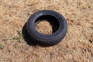 Sarı kuru çimlerin üzerinde duran eski bir lastik. Çevre kirliliği konsepti fotoğrafı. Güneşli bir gün. Yukarıdan görüntüle.