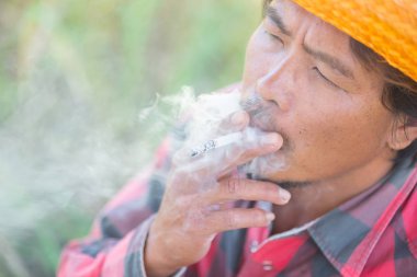 Fotoğraf makinesi ile ağzından duman Sigara çiftçi göz.