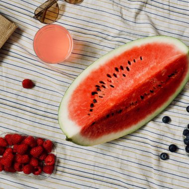 Yaz piknik ayarı, dış toplama kavramı, karpuz, plaj çantası, güneş gözlüğü, yaz şapka, taze mevsim meyveleri ve ferahlık, battaniye, üstten görünüm içki yenileniyor 