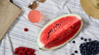 Yaz piknik ayarı, dış toplama kavramı, karpuz, plaj çantası, güneş gözlüğü, yaz şapka, taze mevsim meyveleri ve ferahlık, battaniye, üstten görünüm içki yenileniyor 